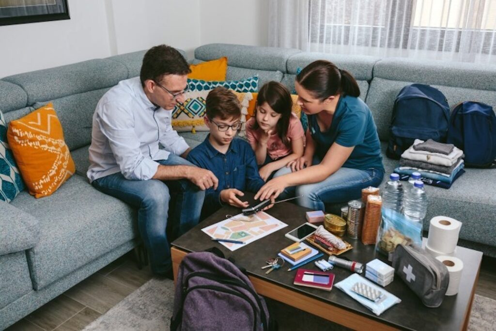 A family of four sitting on a sofa learning about items in a survival kit.