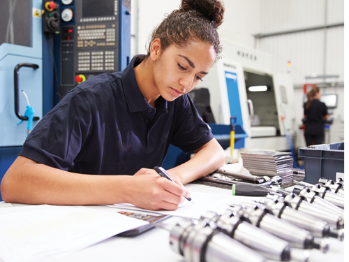 Young woman in a workshop drawing on blueprints.