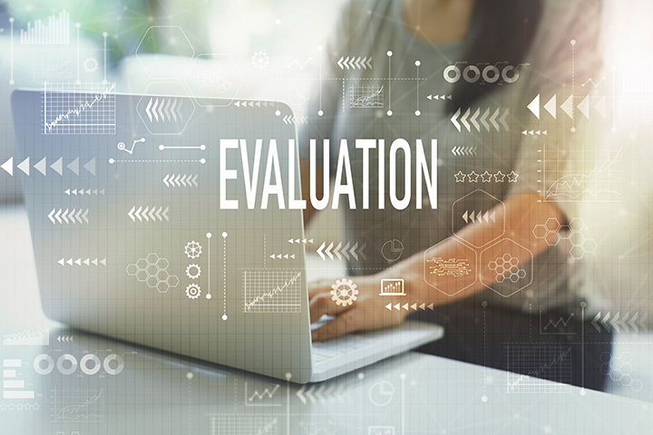 Woman on laptop with the word "Evaluation" glowing in front of the image.