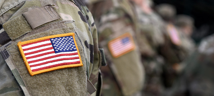 Closeup photo of person in a military uniform, focusing on the USA flag patch on their shoulder.