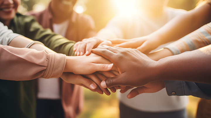 Group of people in a circle with their hands outstretched and overlapping.