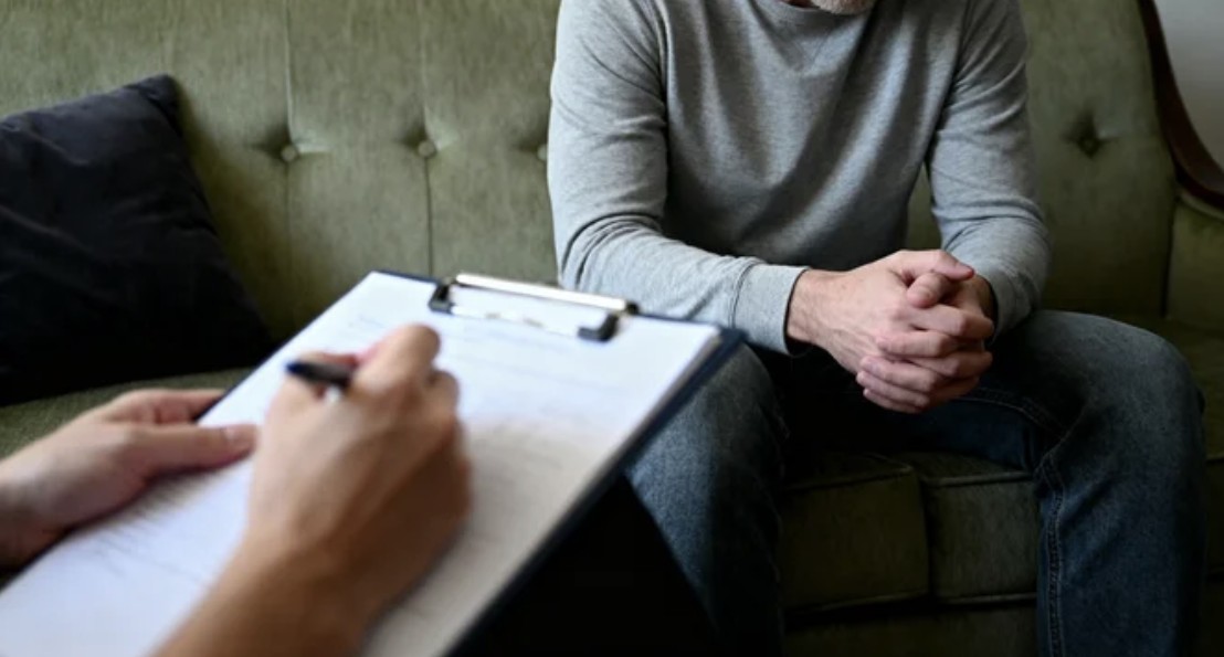 A social worker speaks with a young client while reviewing paperwork and coordinating support services by phone.