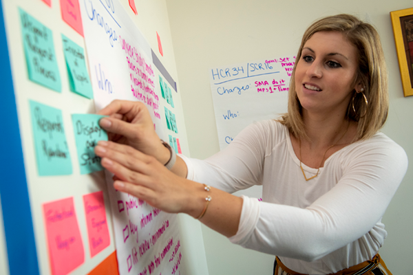 A student prepares a community health intervention on a white board and with colorful sticky notes