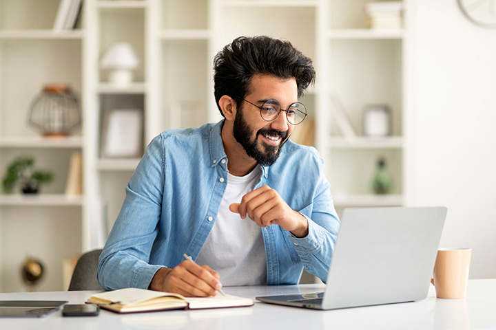 A graduate student works on a research proposal on a laptop.