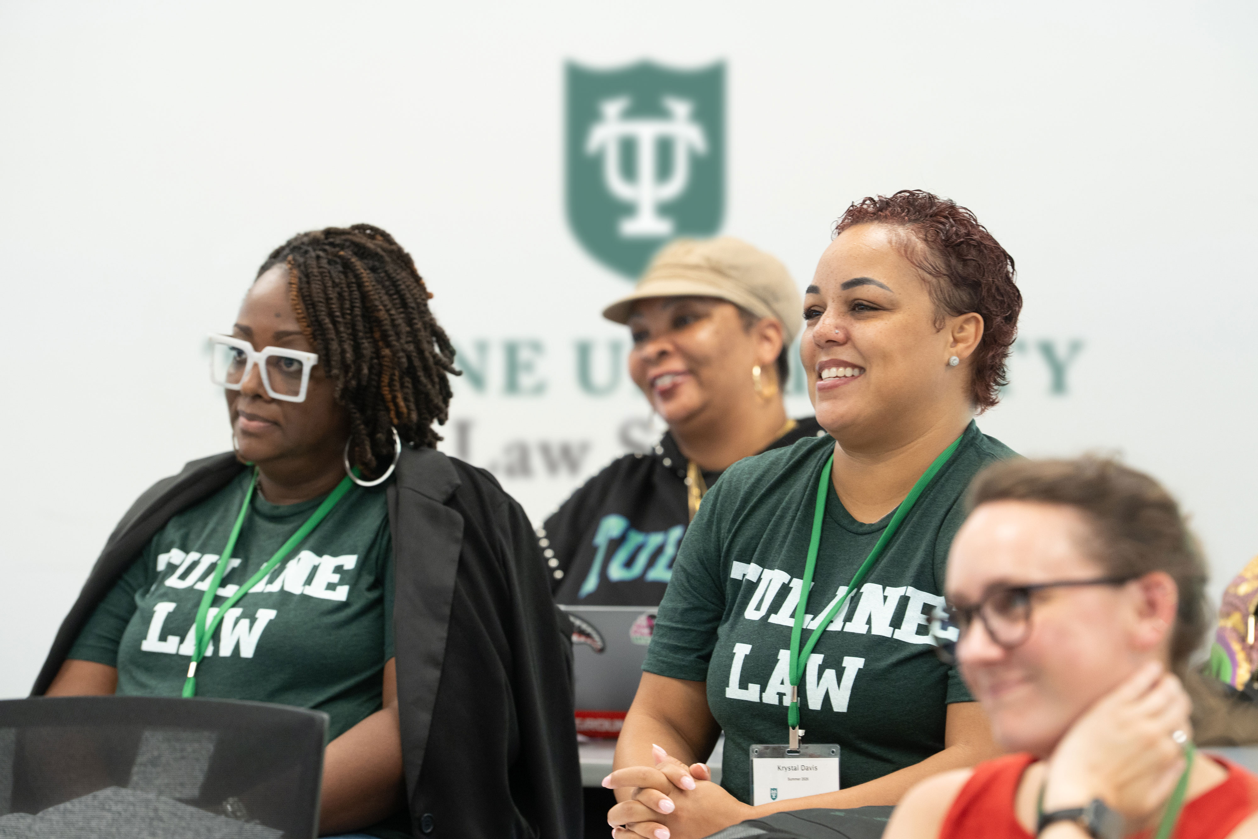 A group of Master of Jurisprudence students wearing Tulane Law shirts engaged and smiling in a lecture